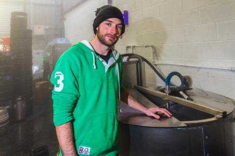Cardiff, United Kingdom, November 26 2015. Brewer Adam stands by brewing equipment at the Crafty Devil Microbrewery, Canton, Cardiff, Wales.